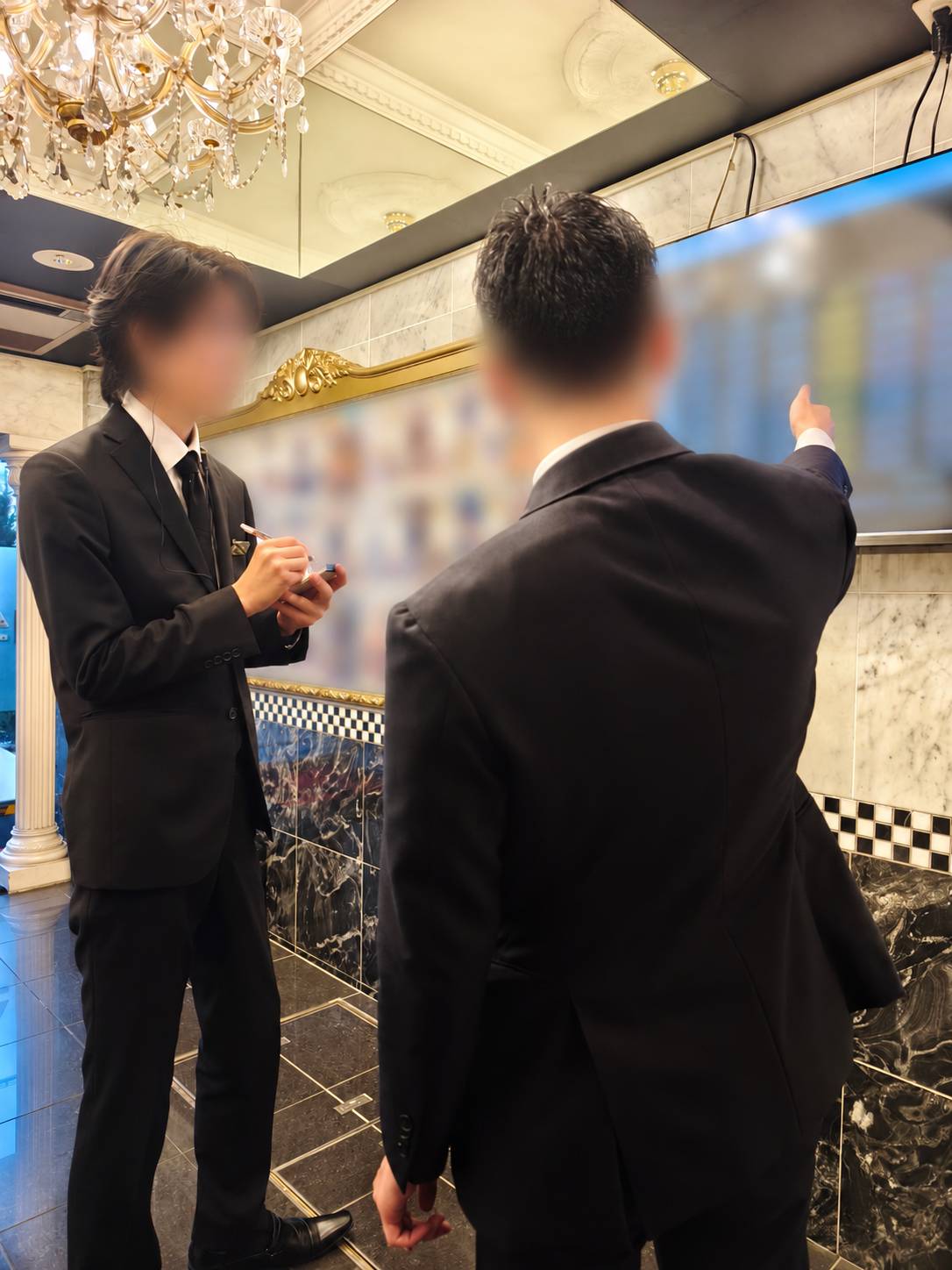 先輩スタッフが新人にパソコン操作を教える研修のイメージ
